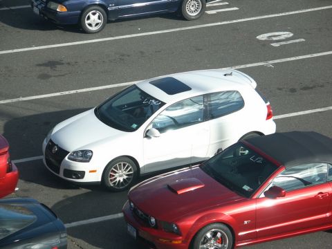 2001 Mercury Grand Marquis - A white Volkswagen Golf GTI is parked in a lot with other vehicles.