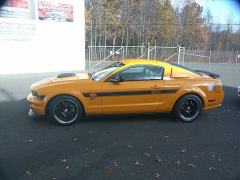 2001 Mercury Grand Marquis - Yellow Ford Mustang GT parked outside a building with signage.