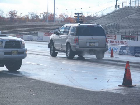 2001 Mercury Grand Marquis - A silver SUV is seen on a drag strip, kicking up dust as it moves. Another vehicle is partially visible on the left.