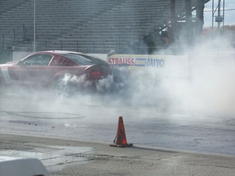 2001 Mercury Grand Marquis - A red Ford Mustang performs a burnout at a race track, obscured by smoke.