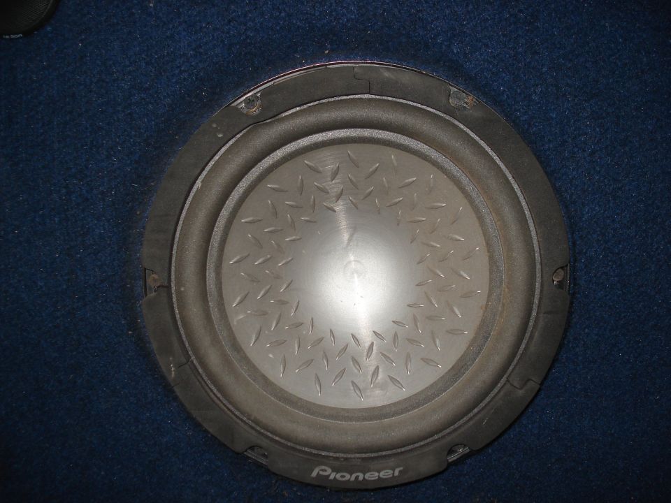Close-up of Pioneer subwoofer with diamond-plate cone mounted in blue carpeted panel