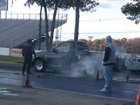 2001 Mercury Grand Marquis - A pickup truck performs a burnout on a drag strip, generating a large amount of smoke.