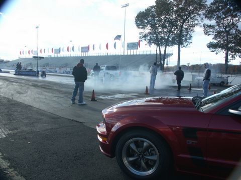 2001 Mercury Grand Marquis - A red Ford Mustang GT is parked at a drag strip with smoke in the background.