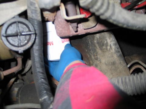 1994 Ford Bronco - A gloved hand is shown removing an oil filter from an engine bay.
