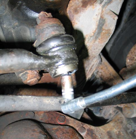 1994 Ford Bronco - Close-up of a vehicle's suspension system, focusing on a ball joint and tie rod end with a socket wrench attached.