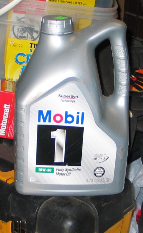 1994 Ford Bronco - A bottle of Mobil 1 motor oil sits on a surface, with other items like cat litter and a Motorcraft box visible.
