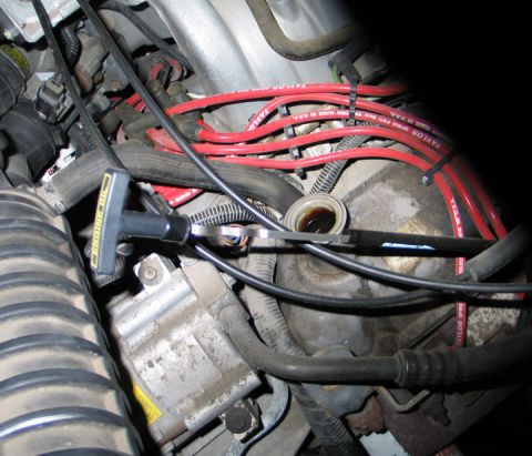 1994 Ford Bronco - Close-up view of an engine bay, focusing on the oil dipstick and red spark plug wires.
