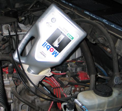 1994 Ford Bronco - Adding oil to an engine using a funnel, with a bottle of Mobil 1 10W-30 in view.