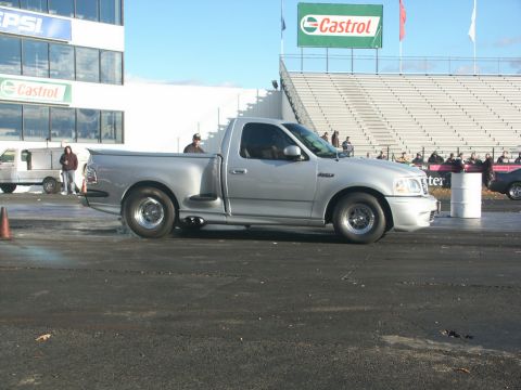 2001 Mercury Grand Marquis - A silver pickup truck is parked on a race track with spectators in the background.