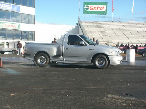 2001 Mercury Grand Marquis - Silver Ford F-150 Lightning pickup truck performing a burnout at a drag racing event.