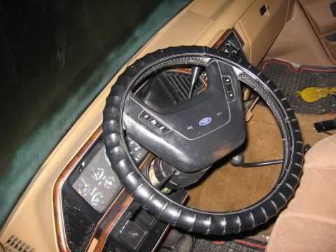 1987 Ford Bronco - The interior of a vehicle, focusing on the steering wheel and instrument cluster. The dashboard features wood grain trim.