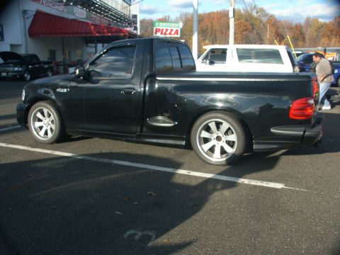 2001 Mercury Grand Marquis - Side view of a black 2001 Ford F-150 Lightning pickup truck at a parking lot.