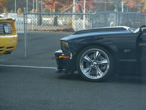 2001 Mercury Grand Marquis - A dark blue Ford Mustang GT is parked next to a yellow car, showing off its custom flames and chrome wheels.