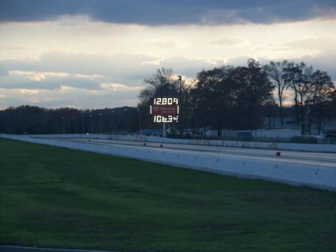 2001 Mercury Grand Marquis - A drag strip is shown with a scoreboard displaying race times under a cloudy sky.