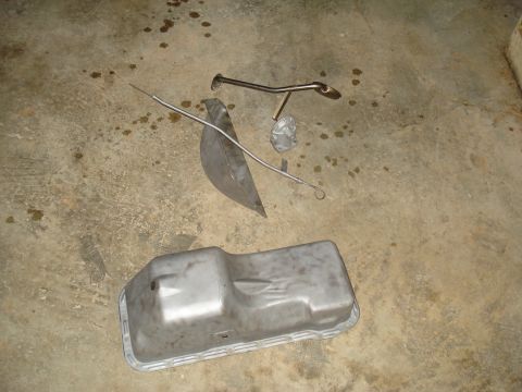 1967 Ford F-250 - Various engine components laid out on a stained concrete surface, likely for maintenance or replacement.