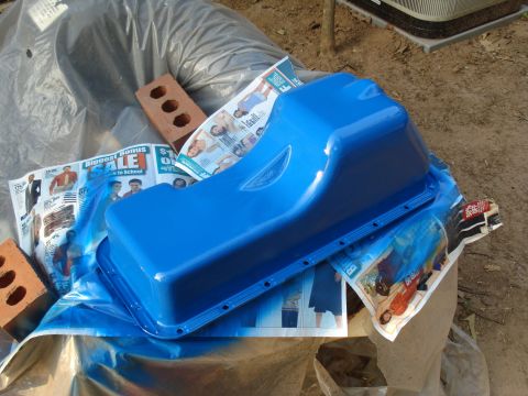 1967 Ford F-250 - A freshly painted blue oil pan sits on top of newspapers, with bricks nearby.