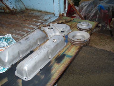 1967 Ford F-250 - Engine parts, including valve covers and pulleys, are laid out on the rusty bed of a pickup truck.