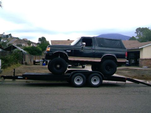 2000 Ford F-250 - Lifted Ford Bronco is transported on a trailer.