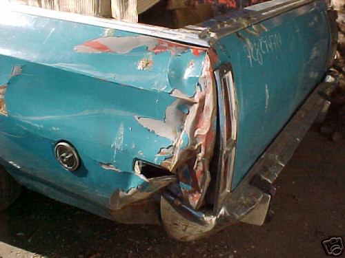 Turquoise car-pickup rear quarter panel crushed in collision, paint torn to red primer