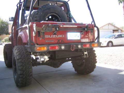 1987 Suzuki Samurai - Rear view of a red Suzuki Samurai showing its aftermarket bumper and spare tire mounted on the back.