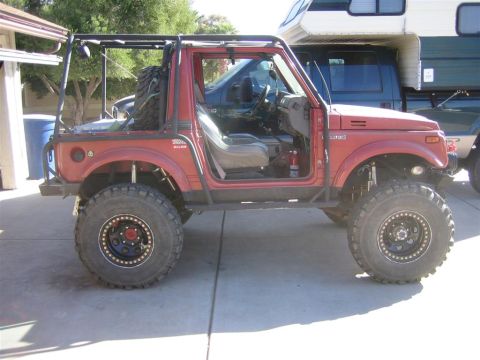 1987 Suzuki Samurai - Modified 1987 Suzuki Samurai shown from the side with its driver's door open and a spare tire mounted.