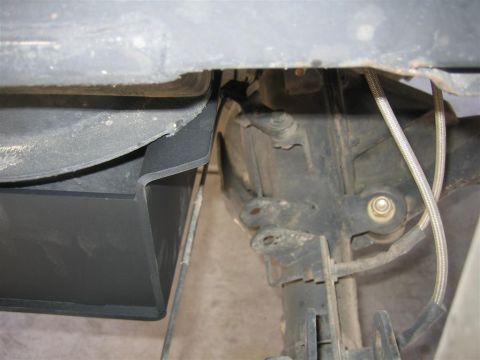 1987 Suzuki Samurai - Close-up of the undercarriage reveals a black plastic shield and braided metal brake lines near the suspension components.