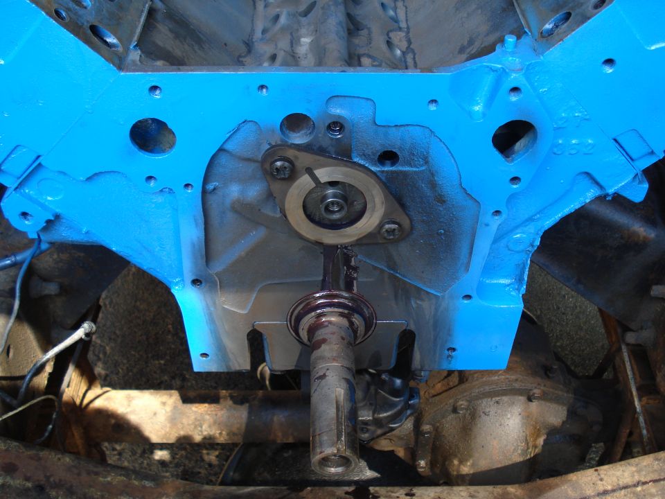Close-up of a blue-painted engine block with a driveshaft extending downwards