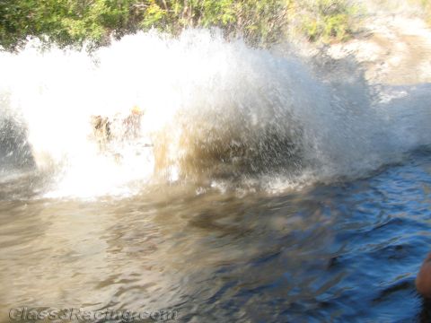 1990 Ford Bronco - massive white spray of water nearly fills the frame as a vehicle plows through a river crossing.