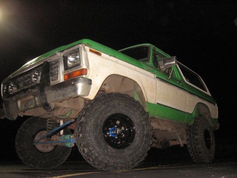 1979 Ford Bronco - This modified Ford Bronco sits high on off-road tires, its two-tone paint scheme visible under artificial light.