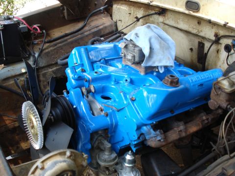 1967 Ford F-250 - The engine bay of a vehicle, a freshly painted blue engine with various components attached.