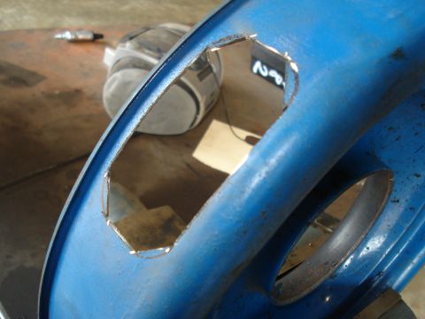 1967 Ford F-250 - Close-up of a blue metal component with an irregular cutout, possibly undergoing modification.