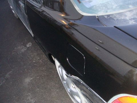 1996 Ford Bronco - Close-up of the rear quarter panel of a black car, showing the fuel door and part of the taillight.