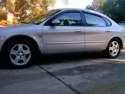 2002 Ford Taurus - Side profile of a silver 2002 Ford Taurus sedan parked on a concrete driveway.