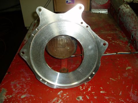 2000 Ford E350 - A metal adapter plate is shown with a light bulb behind the central opening. The Supermotors.net logo is visible.