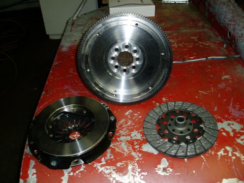2000 Ford E350 - A clutch disc, pressure plate, and flywheel are laid out on a red surface.
