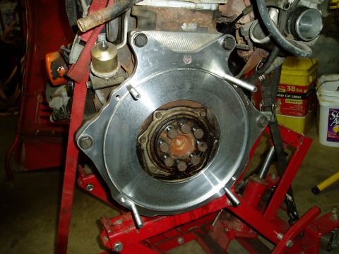 2000 Ford E350 - Close-up of an engine clutch assembly, likely undergoing repair or replacement, supported by a red stand.