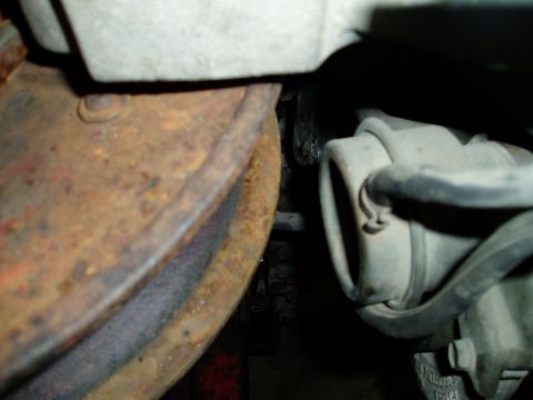 2000 Ford E350 - Close-up view of a heavily rusted brake rotor and a suspension component with hoses.