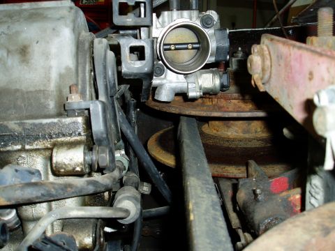 2000 Ford E350 - Close-up view of engine components, including a throttle body and various hoses and brackets.