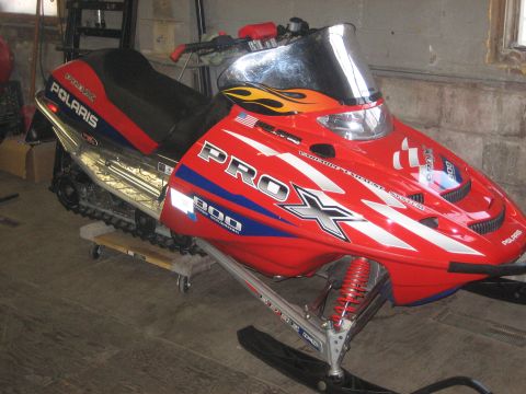 1995 Ford Bronco - A red Polaris snowmobile with "PROX 800" graphics is parked indoors.