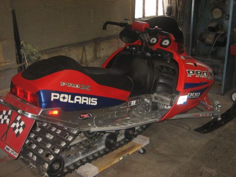 1995 Ford Bronco - A red and blue Polaris snowmobile is parked indoors, possibly in a garage or workshop.