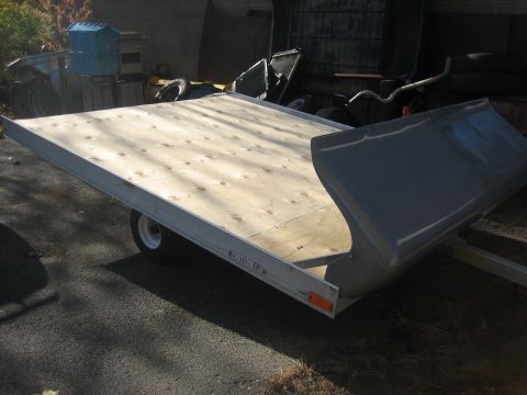 1995 Ford Bronco - A trailer with a wooden deck and a gray cover is parked outdoors.