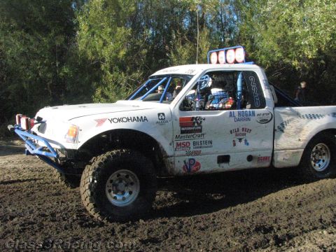1990 Ford Bronco - white off-road race truck numbered 226 with Yokohama and Al Hogan markings sits on muddy terrain by trees.