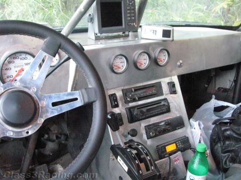 1990 Ford Bronco - close view of an off-road race vehicle dash with speedometer, three gauges, stacked communication radios and a multi-speed shifter.