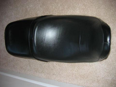 1985 Ford LTD Crown Victoria - A black leather motorcycle seat is shown from a top-down perspective on a carpeted floor.
