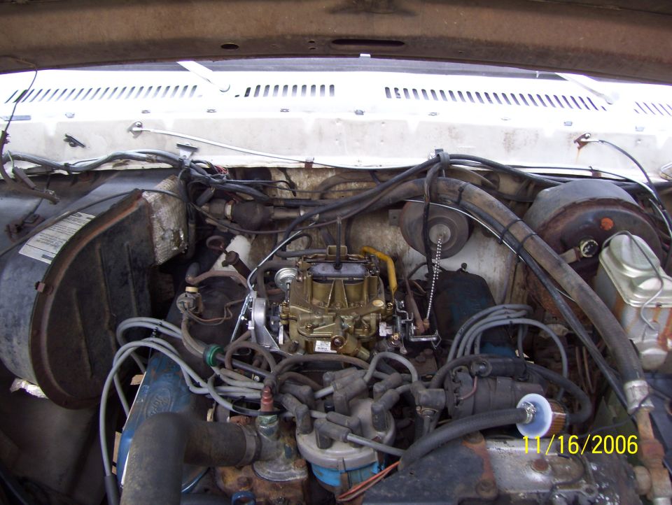 Ford truck engine bay with air cleaner off showing gold carburetor and plug wires
