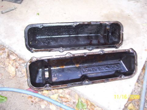 1978 Ford Bronco - Two stamped-steel V8 valve covers lying upside down on a concrete step, dated 11/16/2006, showing the oily inner baffles and old sealant re…