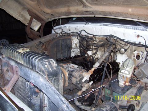 1978 Ford Bronco - Engine bay of an older truck mid-teardown, with the valve covers removed to expose the pushrods and rocker arms on a dusty V8 and the hood…
