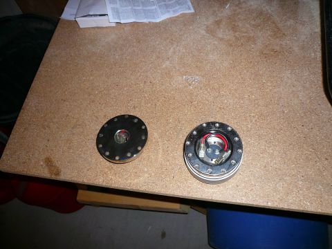1996 Ford Probe - Two steering wheel hubs, one with visible wiring, are placed on a particle board surface next to some papers.