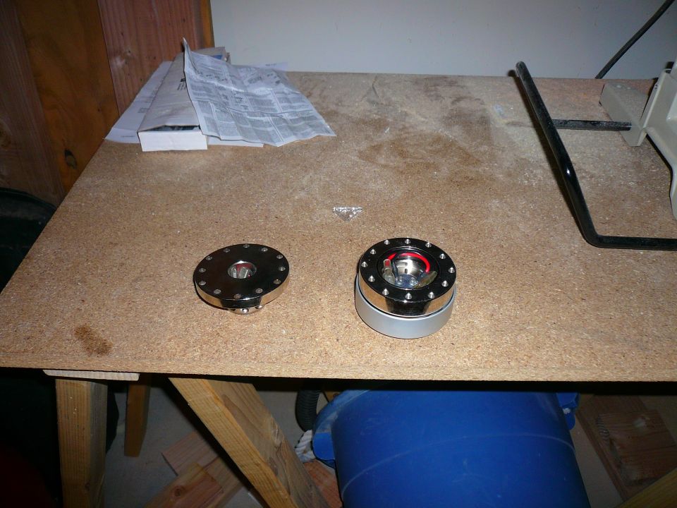 Two chrome and silver steering wheel quick release hubs on a workbench