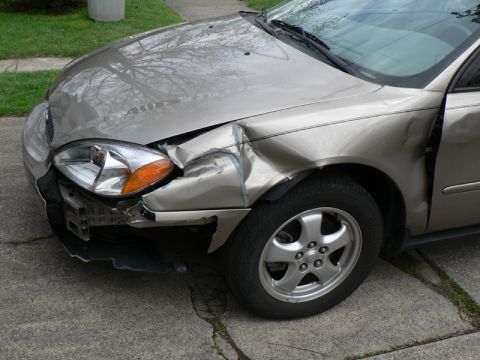 2004 Ford Taurus - Front passenger side of a 2004 Ford Taurus shows significant damage to the fender and bumper area.